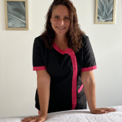 praticienne en blouse appuyée contre sa table de massage