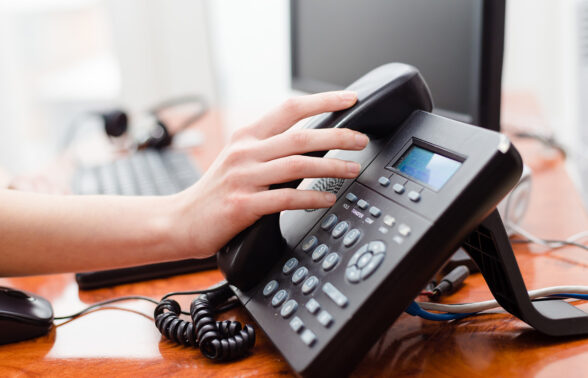 une main se pose sur un téléphone fixe de bureau. - Agrandir l'image, fenêtre modale